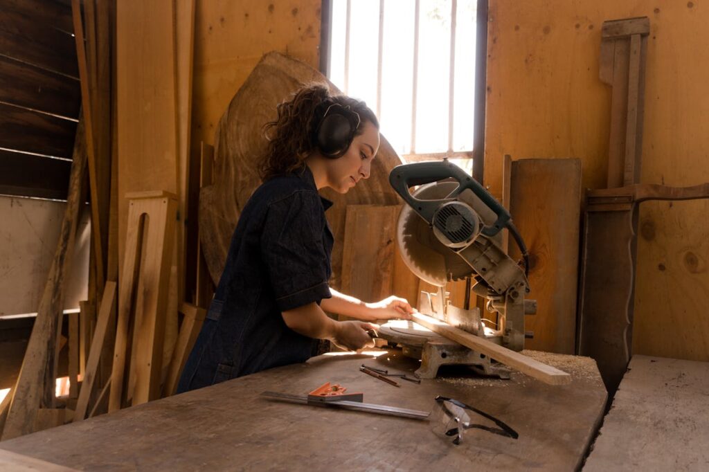 Dedicated female carpenter using a circular saw in woodworking studio, focused on craftsmanship and precision.