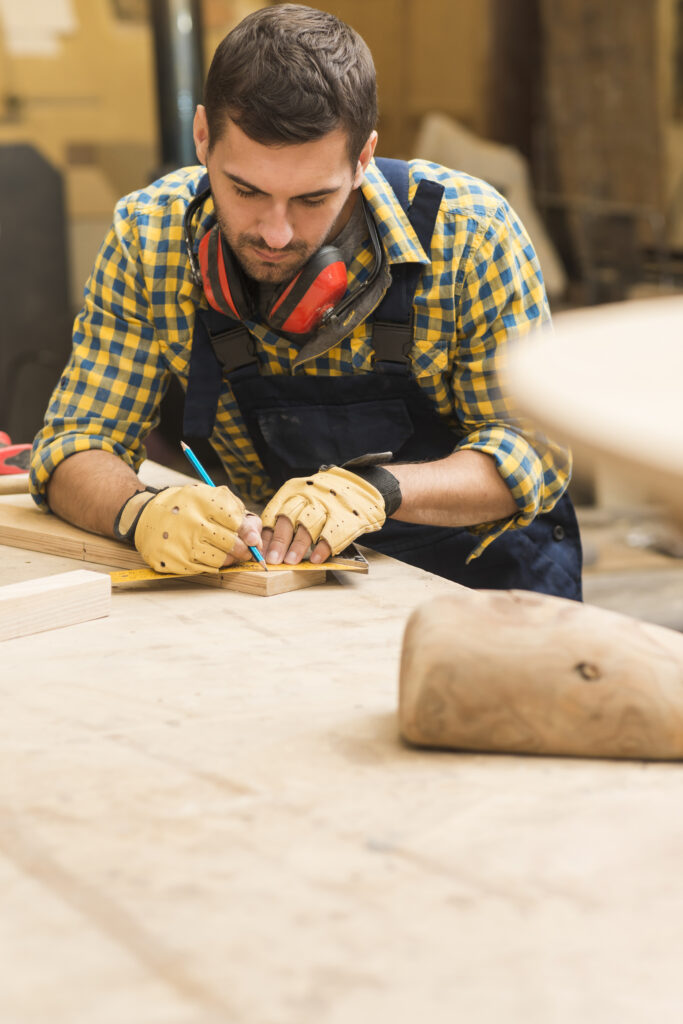 male-carpenter-measuring-wooden-block-with-ruler-pencil
